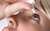 Woman putting eye drops in eye